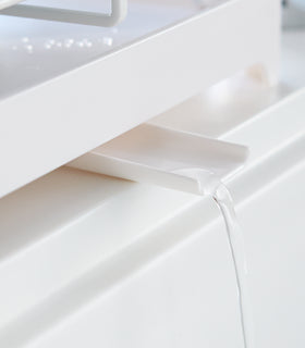 Close up of white Dish Rack water spout draining water into sink by Yamazaki Home. view 7