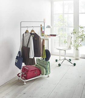 White Rolling Coat Rack holding school clothes, accessories and bags by Yamazaki Home. view 3