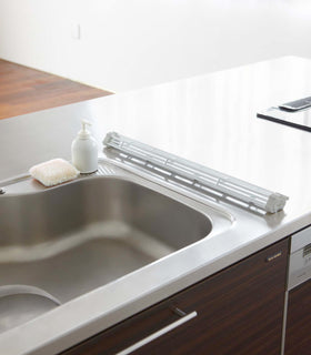 White Over the Sink Folding Drying Rack with folded or rolled up on kitchen counter.
 view 8