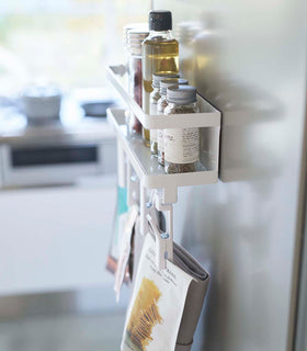 Side view of white Magnetic Organizer with Easy-Grip Rotating Clips holding spices and kitchen items by Yamazaki Home. view 3