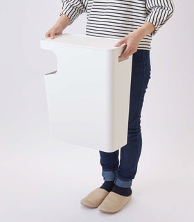 Side view of white Side Table Trash Can being held by model on white background by Yamazaki Home. view 6