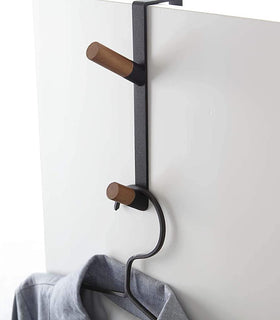 Close up view of black Over-the-Door Hook holding shirt on white background by Yamazaki Home. view 10
