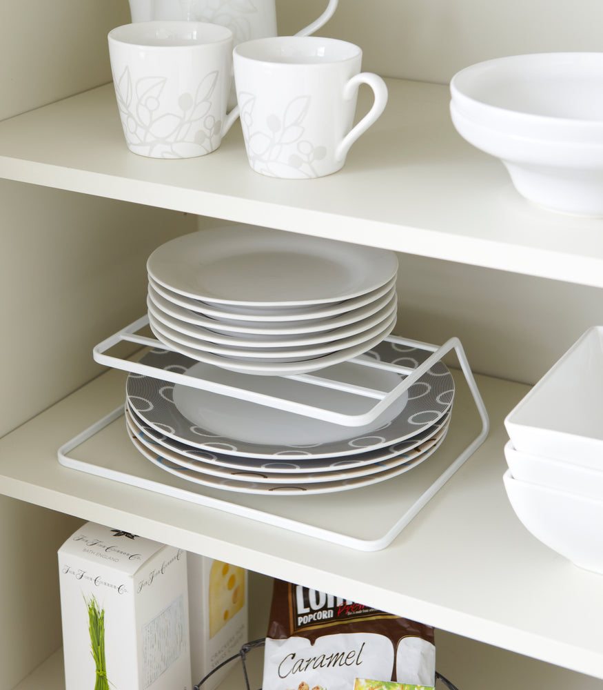 View 2 - White Dish Riser holding plates on shelf by Yamazaki Home.