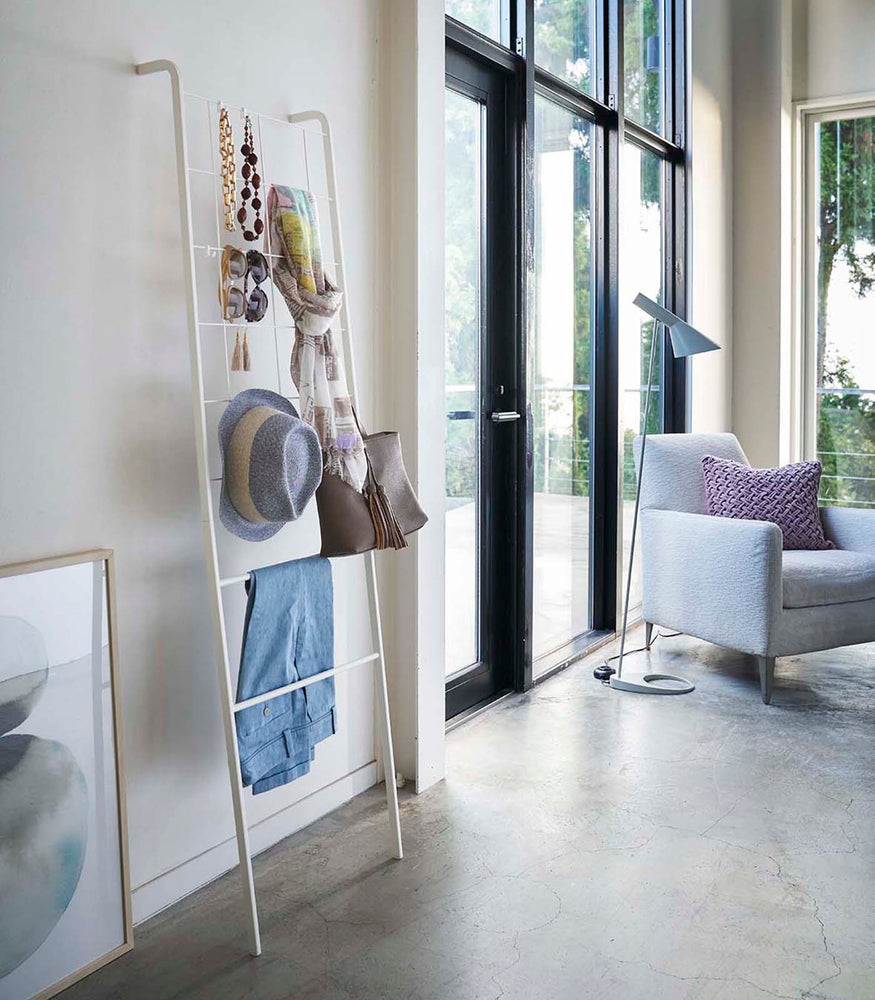 View 2 - Side view of white Leaning Ladder with Grid Panel holding accessories in living room by Yamazaki Home.