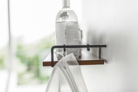 Side view of Wall-Mounted Shelf holdling cleaning items and mesh bag by Yamazaki Home. view 8