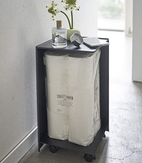 Back side view of black Rolling Bathroom Organizer holding toilet paper in bathroom by Yamazaki Home. view 11