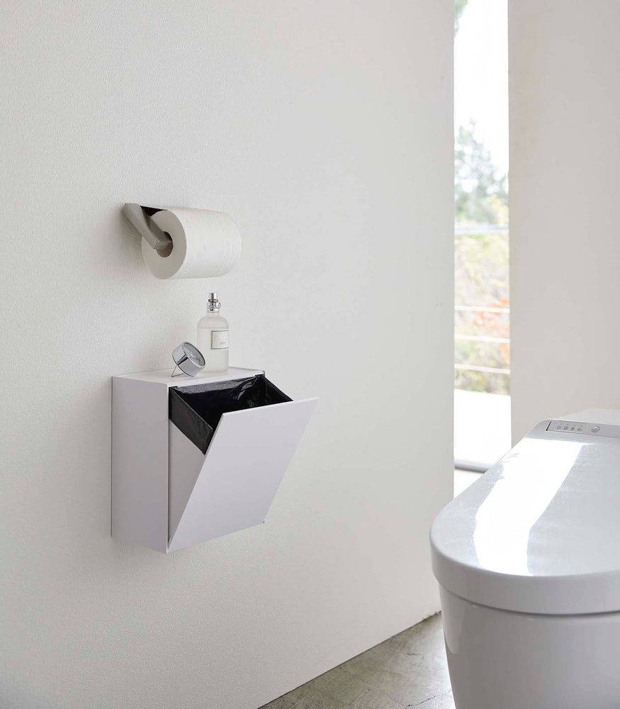 View 3 - White Wall-Mount Storage open and holding trash bag on bathroom wall by Yamazaki Home.