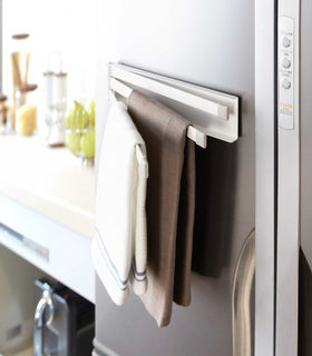 Side view of white Magnetic Dish Towel Hanger holding towels in kitchen by Yamazaki Home. view 3