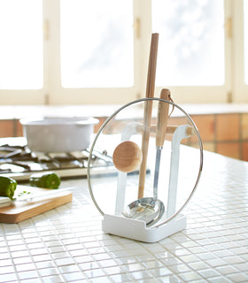 White Lid & Ladle Stand holding pot cover and kitchen utensils on kitchen countertop by Yamazaki Home. view 3