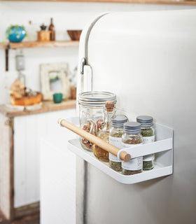 White Magnetic Storage Caddy holding spices and vinegar in kitchen by Yamazaki Home. view 3