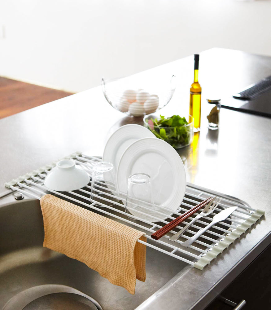 View 4 - Over-the-Sink Dish Drainer holding dishes and silverware in kitchen by Yamazaki Home.