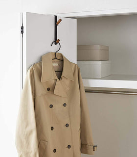 Black Over-the-Door Hook on closet door holding jacket by Yamazaki Home. view 9