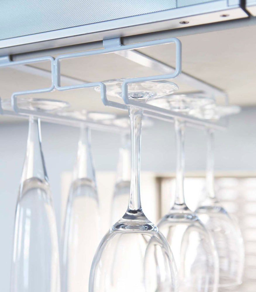 View 5 - Close up view of white Undershelf Stemware Holder holding glasses by Yamazaki Home.