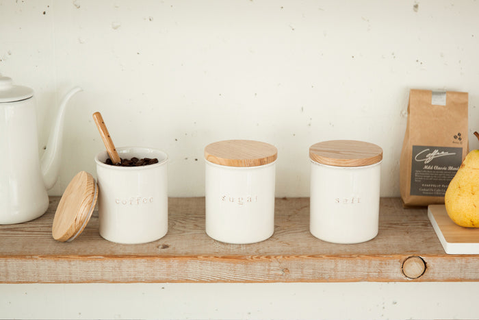 Front view of three Yamazaki Home canisters (sugar, coffee salt) on a wooden shelf 