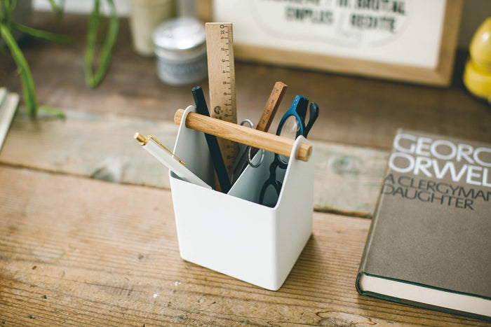 Pen and Desk organizer holding various desk accessories and pens next to a book by George Orwell on a rustic desk