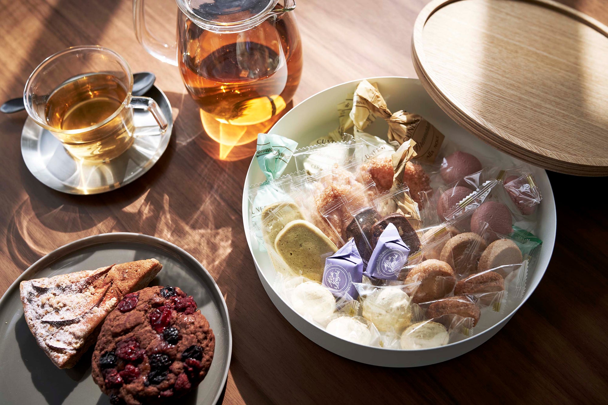 Yamazaki Home circular storage dish with various candy on a modern kitchen table with light pooling in from the corner. 