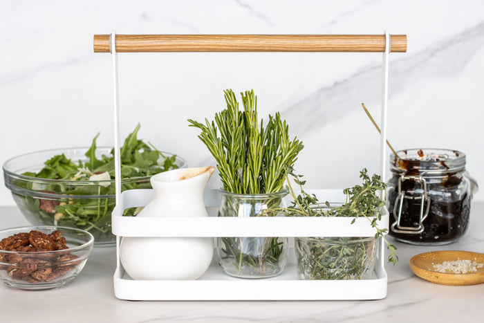 Herb rack with various herbs and a white container on a white background