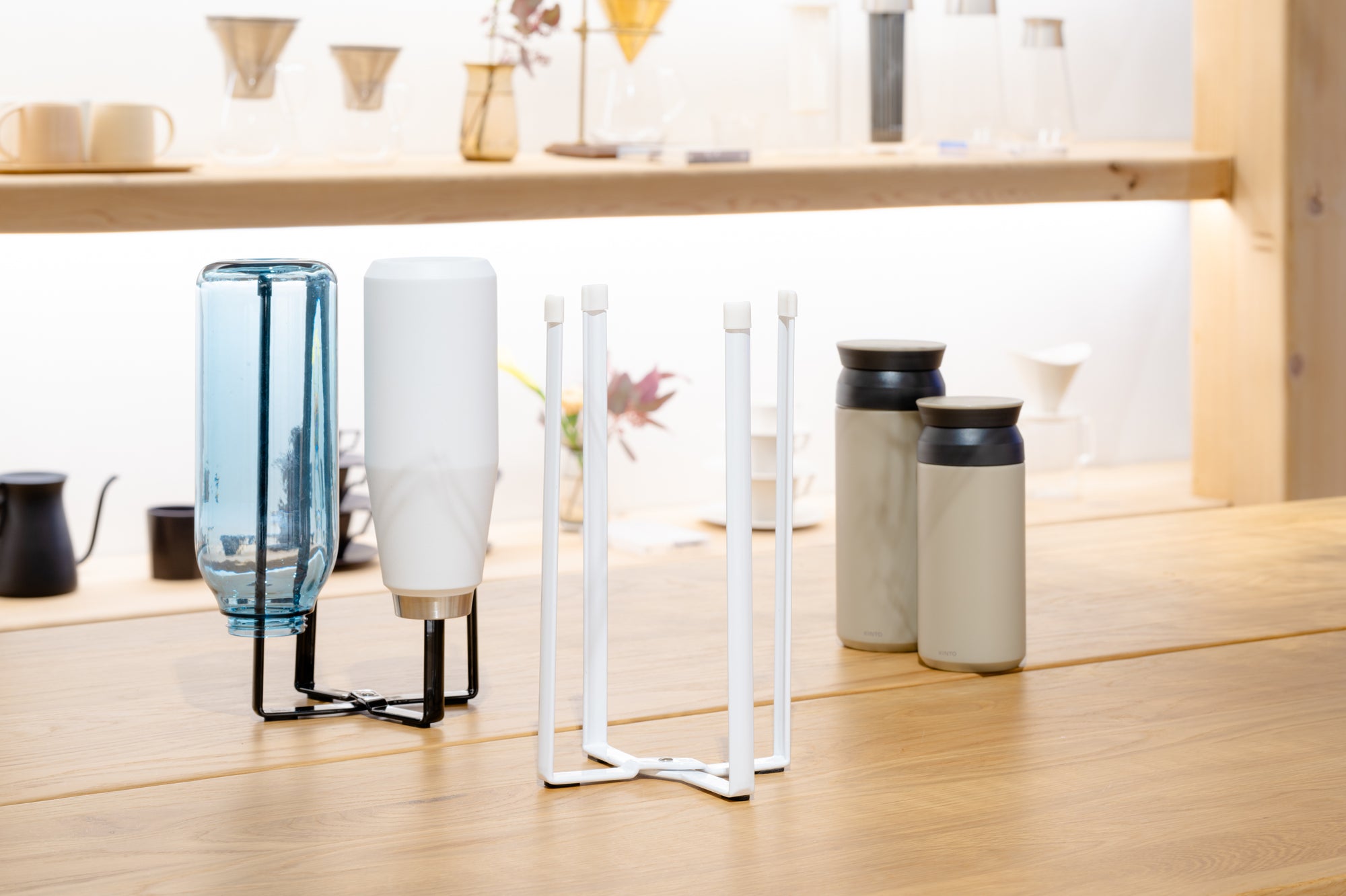 Two collapsible bottle dryers in white and black from Yamazaki Home holding various KINTO water bottles and tumblers, styled in the KINTO NYC Store Front