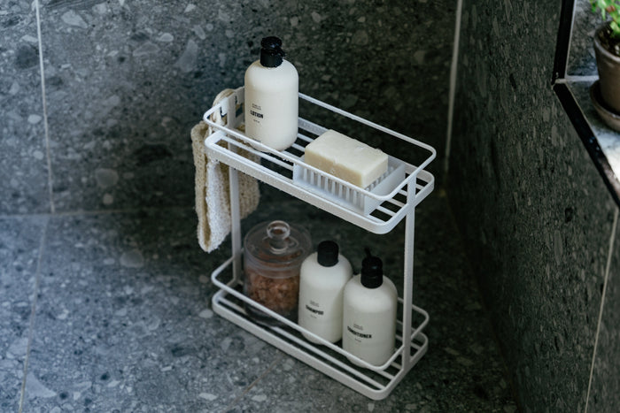 Stone shower with shower stand from yamazaki home holding various products luxury spa items from Public Goods.