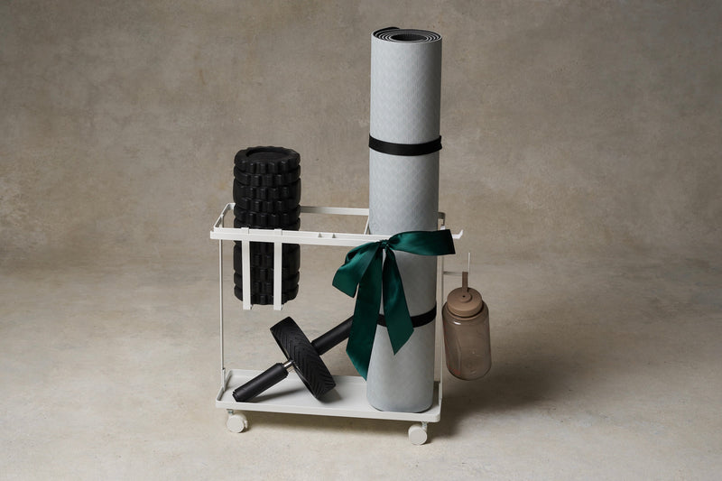 White steel rolling fitness storage cart from Yamazaki Home holding new pilates mat, foam roller, ab workout wheel, and water bottle. 