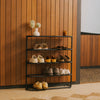 Black 4-tier metal shoe rack with tabletop against a wood-paneled wall, holding 8 pairs of shoes, topped with a vase and candle.