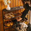Woman grabbing shoes from black metal multi-tier entryway shoe rack organizer filled with sandals and sneakers