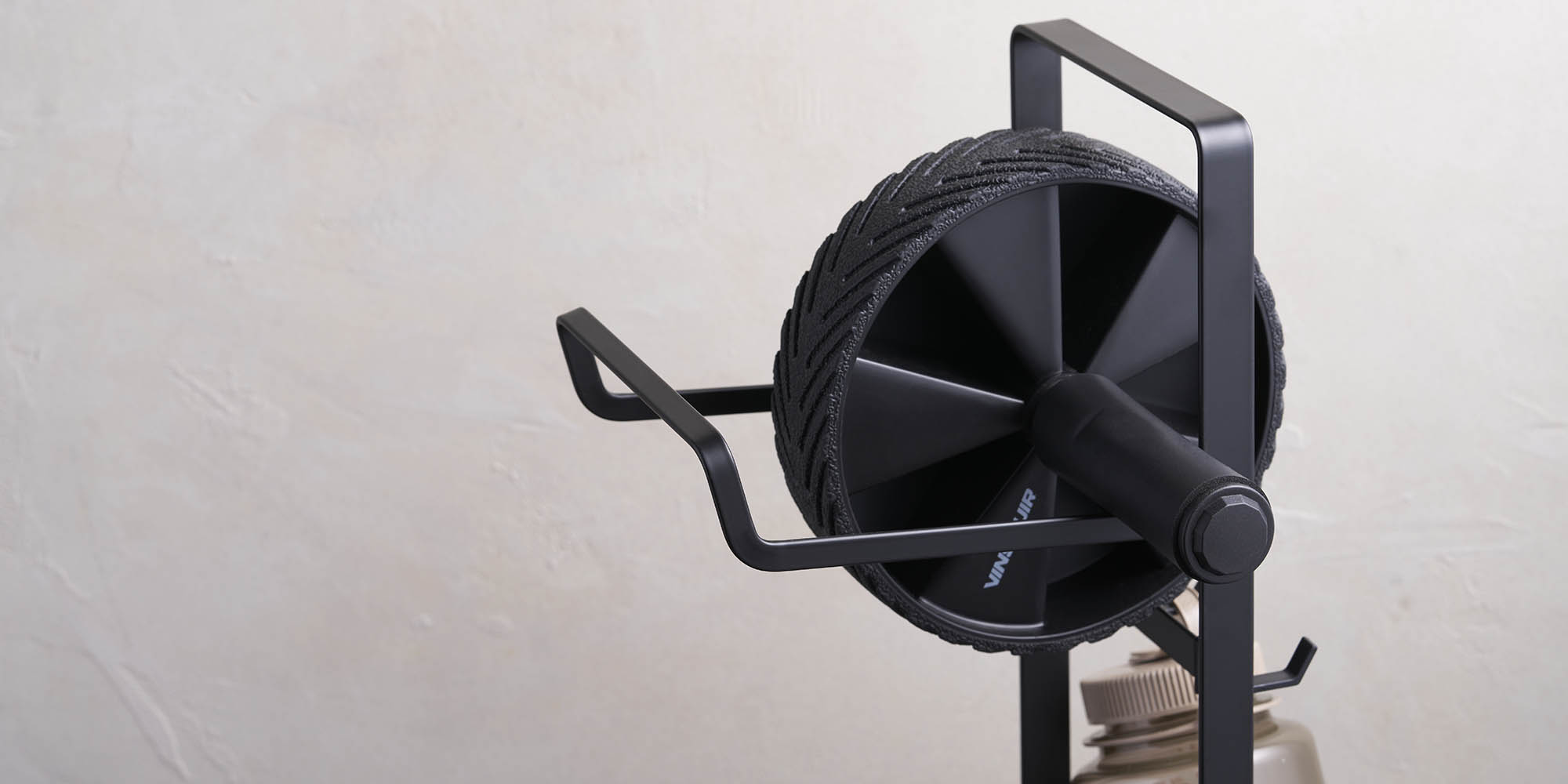 Black fitness equipment rack holding an ab roller and water bottle