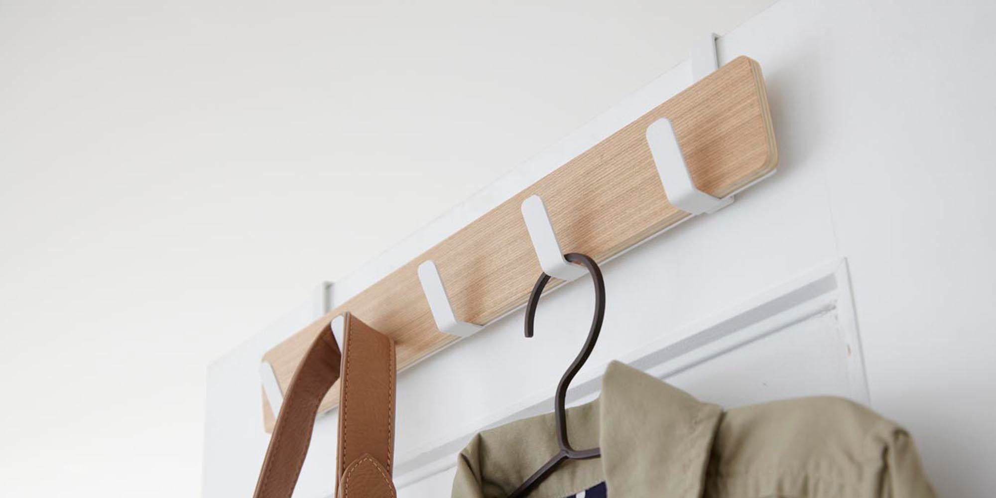 Yamazaki Home Ply Over-the-Door Rack in Ash holding a hanger with a khaki shirt and a leather purse strap.