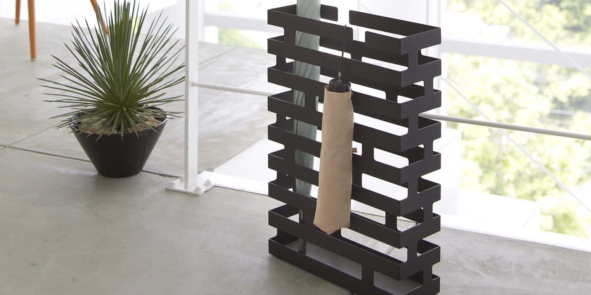 Rectangle Umbrella stand holding two umbrellas in black from Yamazaki Home in a modern home's entryway 