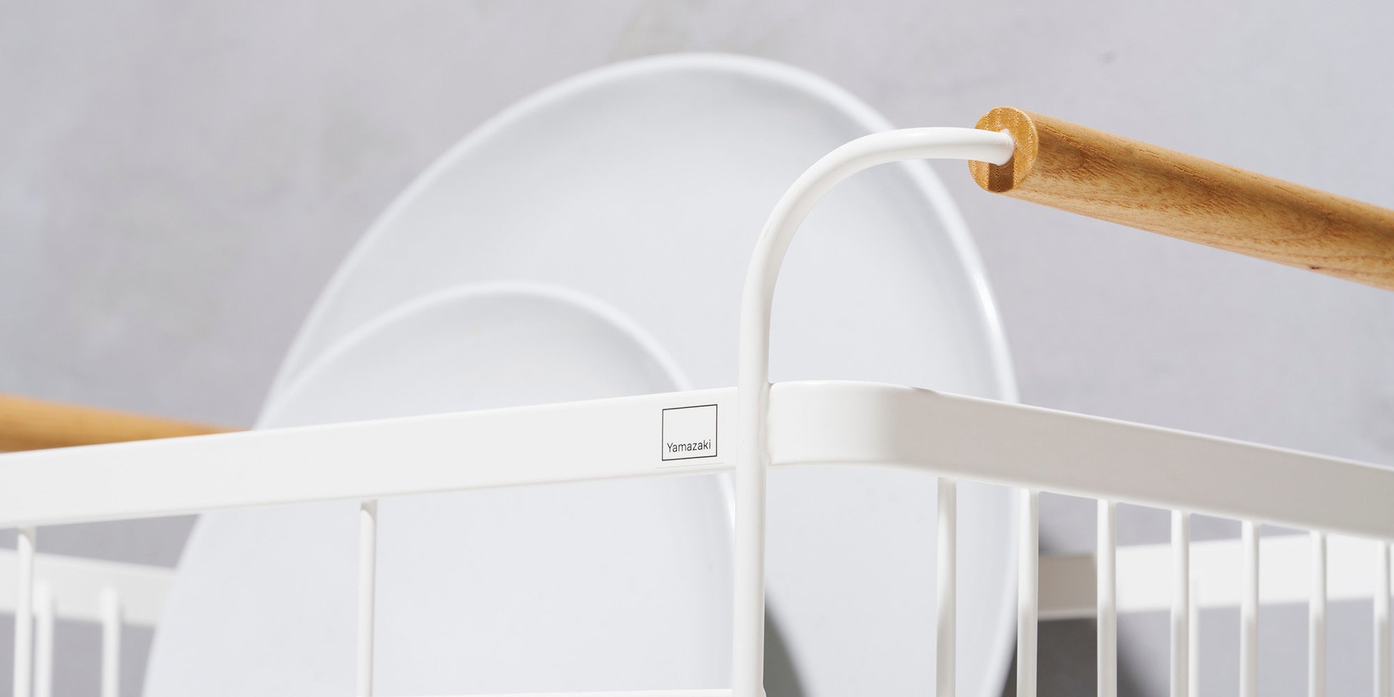 White steel dish rack with wood handles holding two dinner plates. Closeup image for collection cover image. 