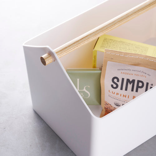 White storage caddy with wood handle holding crackers and snacks