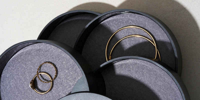 Stacked jewelry organizer close up image, holding various gold jewelry.