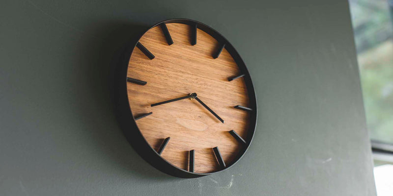 Wall clock hanging on the wall made of steel and wood. Time shows 4:41 