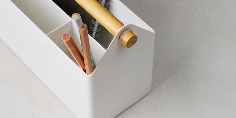 Pen and Desk Organizer in white steel with wood handle. Organizer is holding notebook and three pencils.