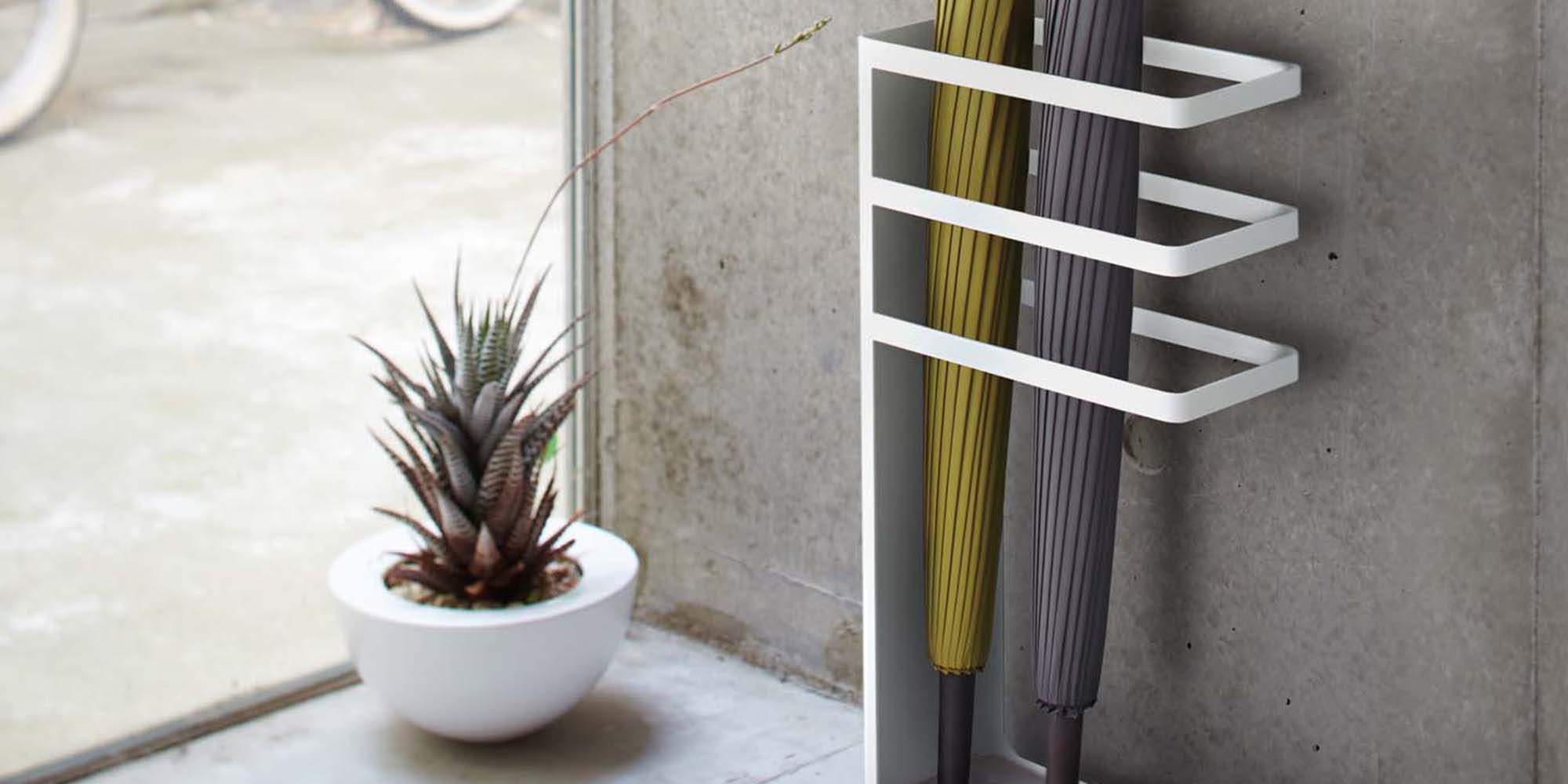 Yamazaki Home Layer Umbrella Stand in White in a modern entryway holding a green umbrella and a gray umbrella.