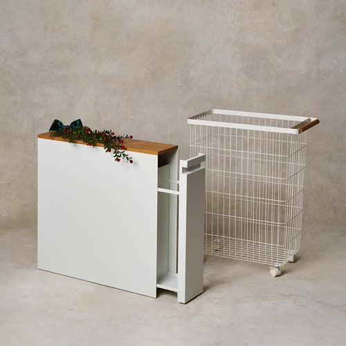 White cabinet with wooden top and wire laundry basket on a beige background