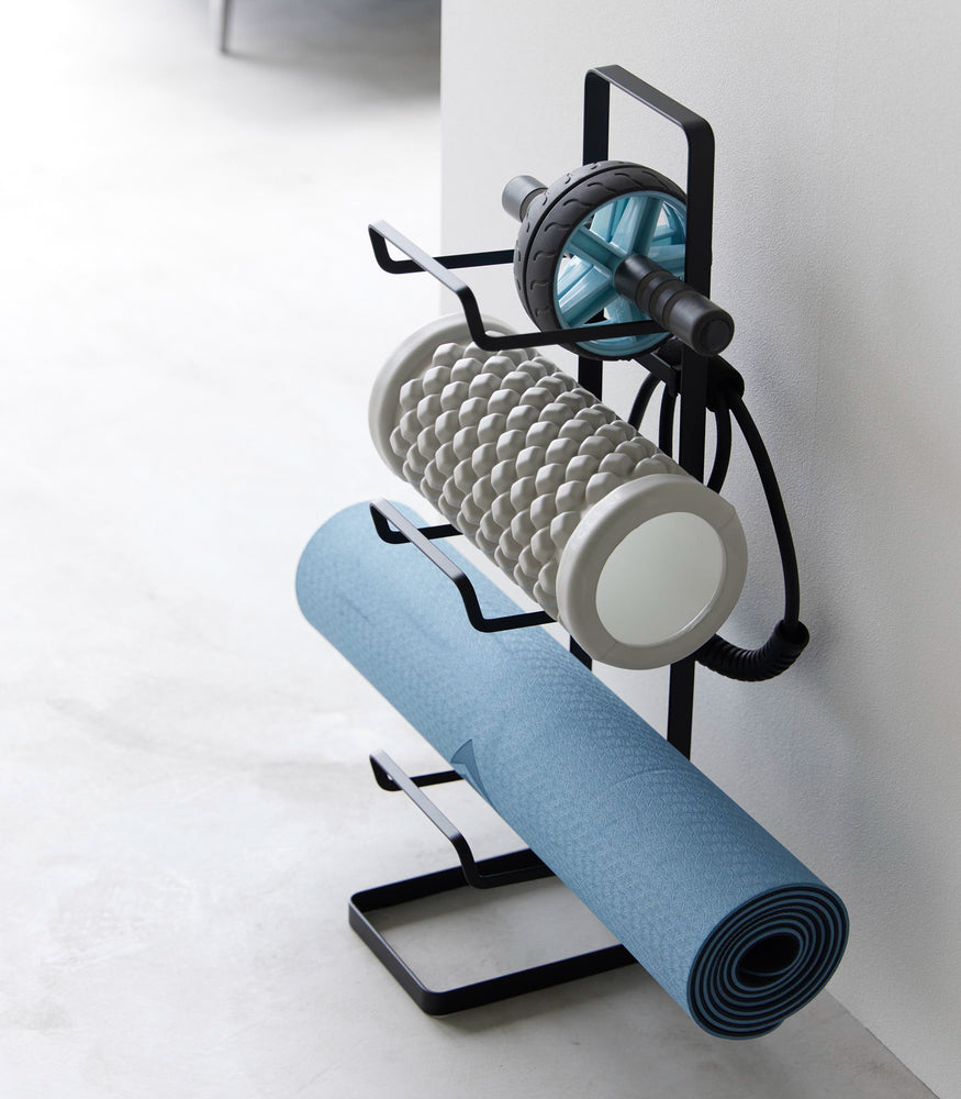 View 13 - Aerial view of Yamazaki Home Black Fitness Equipment Storage Rack holding a yoga mat and foam rollers.