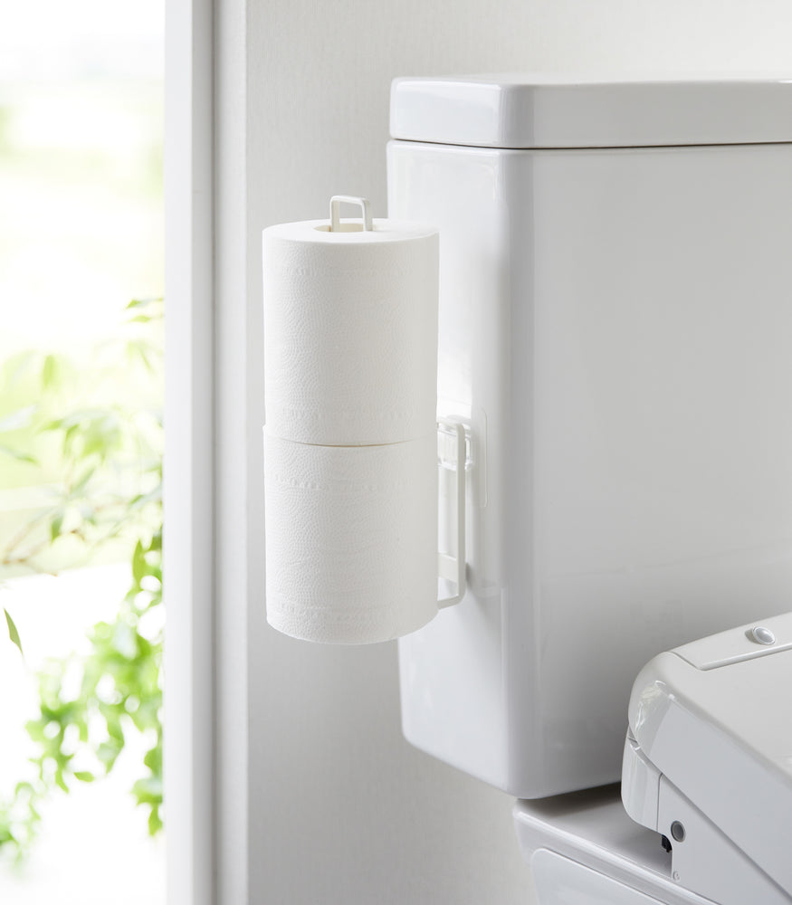 View 2 - White Yamazaki Home Traceless Adhesive Toilet Paper Holder attached to the side of a toilet