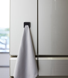 Frontal view of black Yamazaki Home Traceless Adhesive Towel Holder with towel inserted view 12