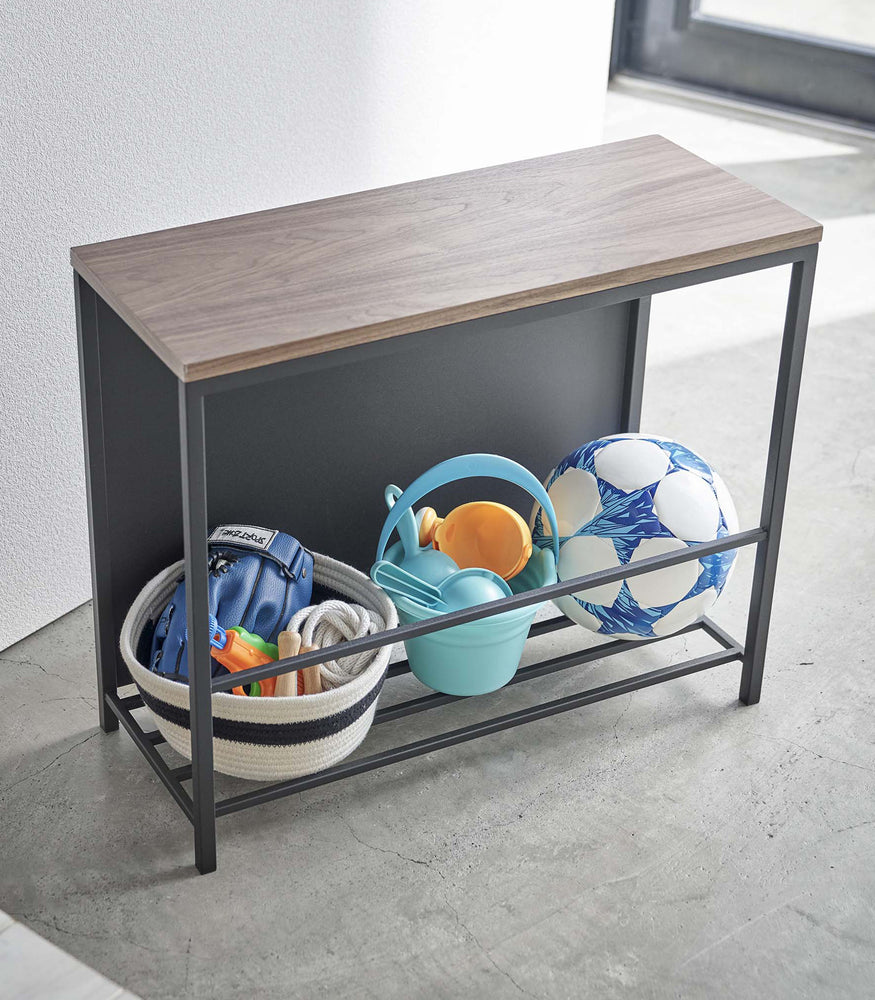View 13 - Side view of black Yamazaki Discreet Entryway Storage Shelf with toys and balls inside