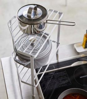 Aerial view of White Two-Tier Corner Riser holding pot and saucepan in kitchen by Yamazaki Home. view 4