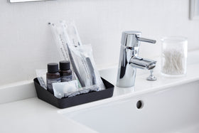Medium black Accessory Tray holding beauty products on bathroom sink counter by Yamazaki Home. view 11