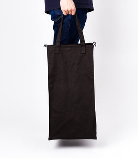 Side view of a person holding the liner of the small Laundry Hamper with Cotton Liner in black by Yamazaki Home by the handles. view 10