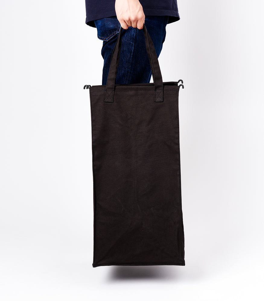 View 10 - Side view of a person holding the liner of the small Laundry Hamper with Cotton Liner in black by Yamazaki Home by the handles.