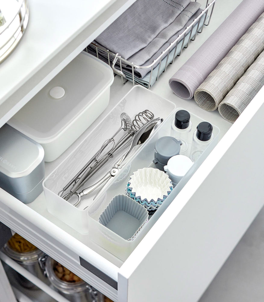 View 49 - Two deep stackable clear organizers are placed in a bathroom drawer, organizing makeup tools and small bottles, neatly placed next to each other.