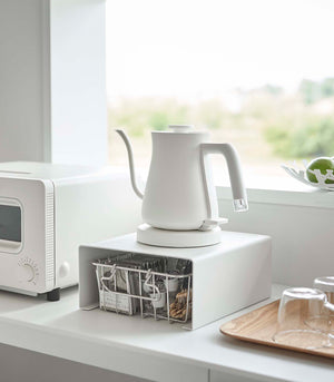 White Yamazaki Home Stackable Countertop Shelf with a kettle above and a basket underneath