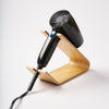 Hair Dryer and Iron Stand - Wood in Ash by Yamazaki Home holding a black hair dryer with a white background.