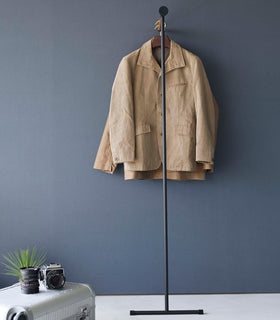 Frontal view of coats hung on black Yamazaki Home Clothes Steaming Leaning Pole Hanger view 15