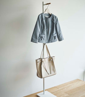 White Yamazaki Coat Rack with a jacket and purse hanging on it in an entryway view 8