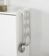 A close-up image of kitchen utensils hanging from hooks placed along the top ridge of the Concealable Spice Rack by Yamazaki Home in white.